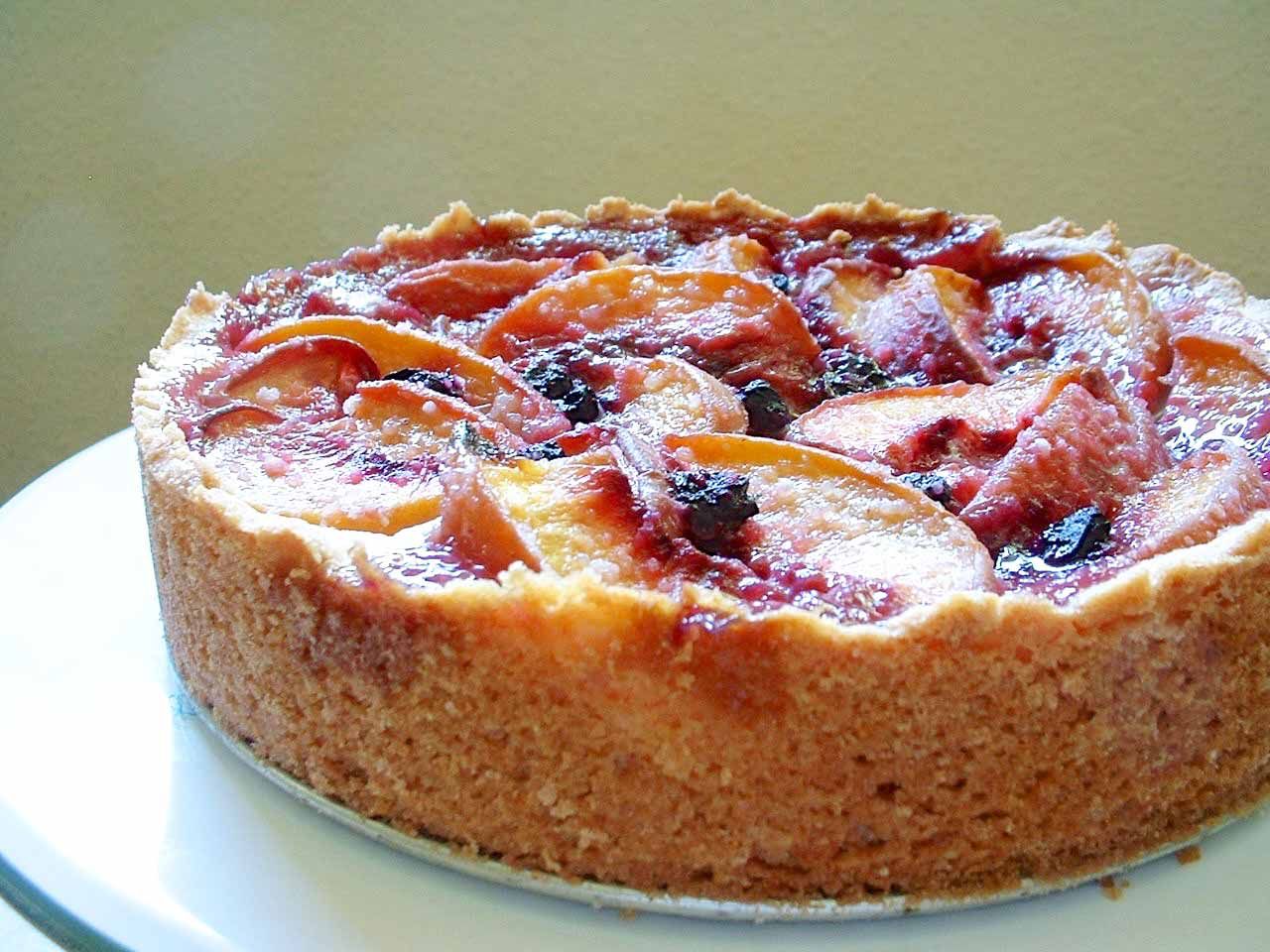 A peach and blueberry cake with a crumbly crust on a plate