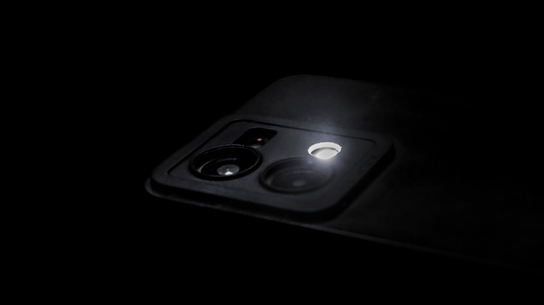 A smartphone's camera bump in the dark with the flash turned on.