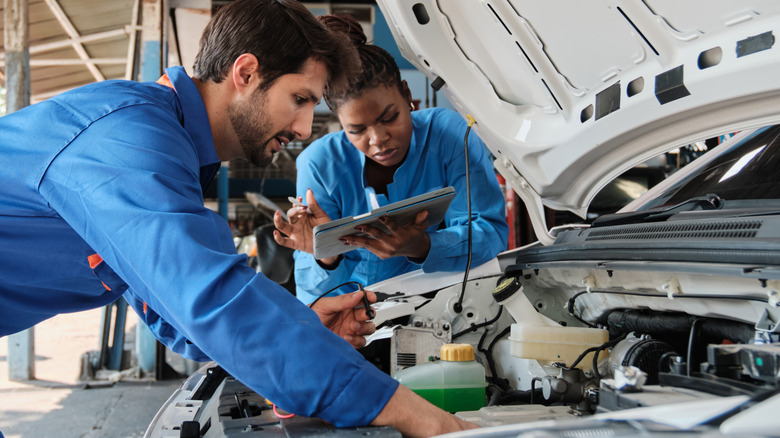 Two auto mechanics check under the hood