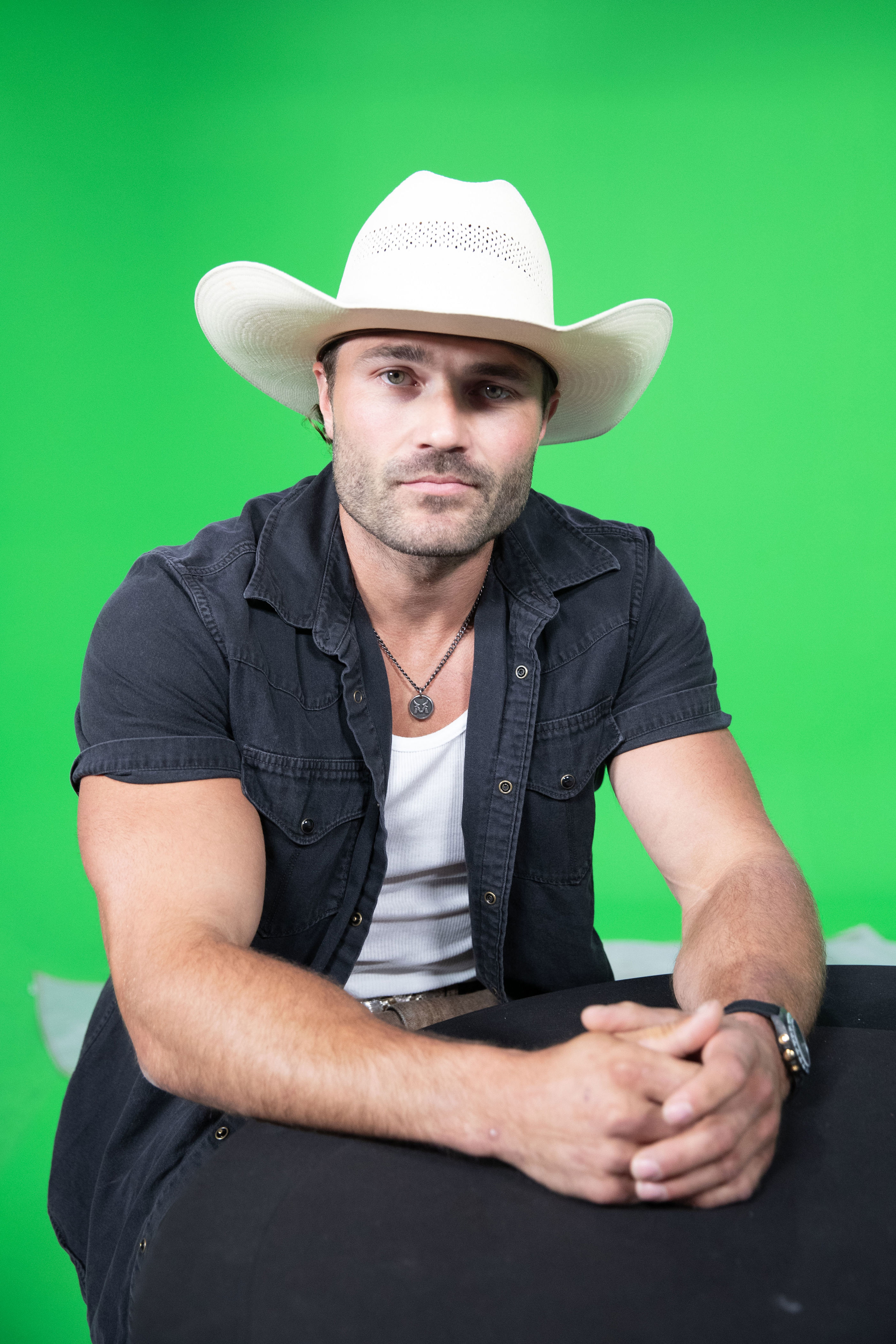 Steven McBee Jr. from McBee Dynasty: Real American Cowboys, wearing a white cowboy hat and black shirt, against a green background.