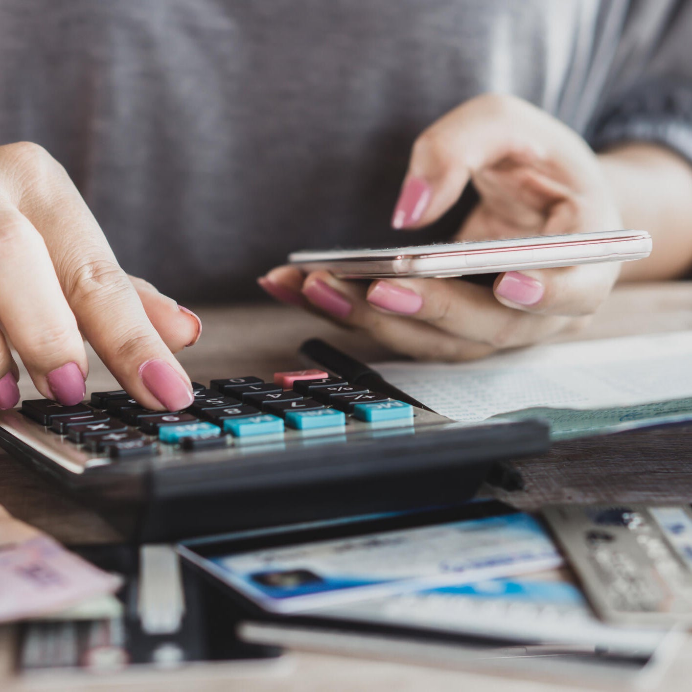 woman hand calculating her expenses and debt from credit cards with smart phone