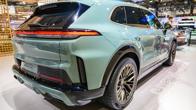 Close-up of a rear three-quarter of a new teal-colored Porsche Cayenne Electric on public display.