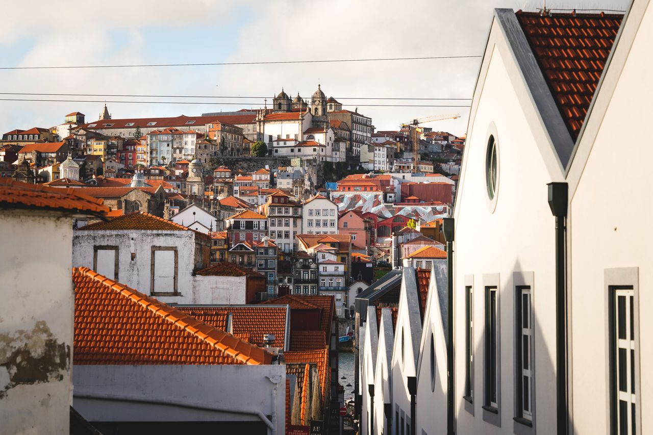 View of a historic cityscape with hillside buildings and red rooftops featuring distant architectural details