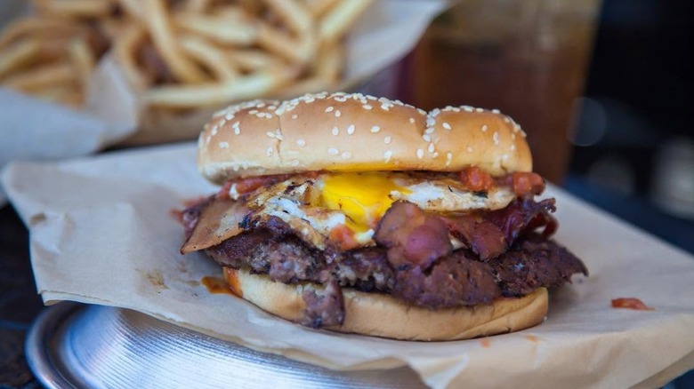Hangover burger with bacon and fries blurred in background