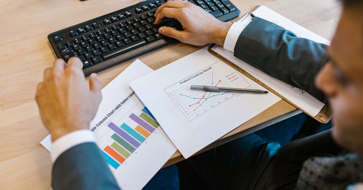 Business professional reviewing charts at desk, analyzing financial trends.