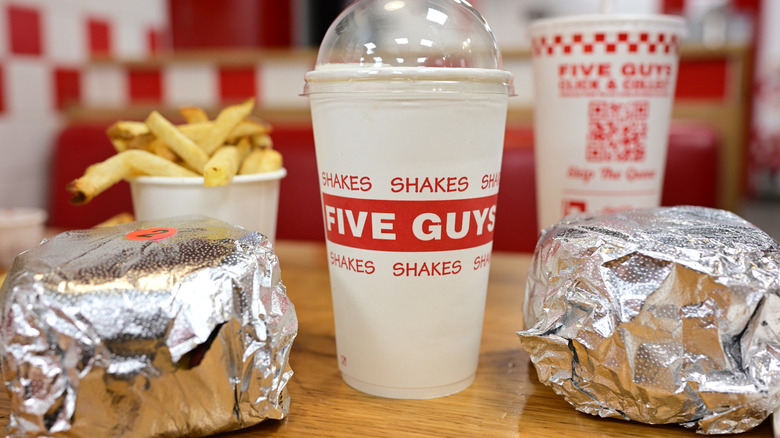 Five Guys burgers with a shake and a bucket of fries on a table.