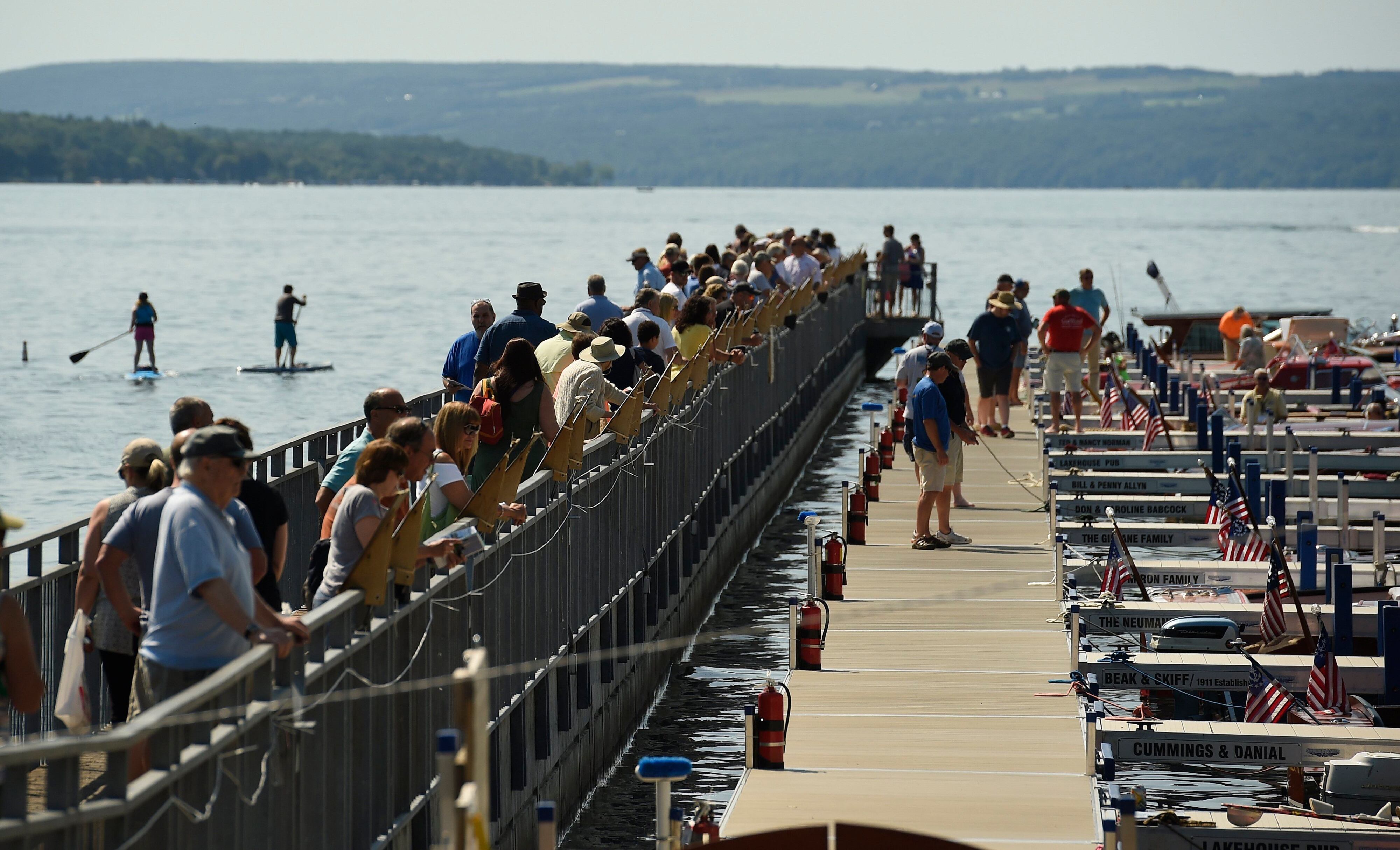 Spectators look at antique boat tied to their slips on Skaneateles Lake on the last day of the Annual Antique and Classic Boat Show in 2017. The three day event drew thousands. In addition to the boats in the water were were boats in a land display at Clift Park. Dennis Nett | dnett@syracuse.co, SYR