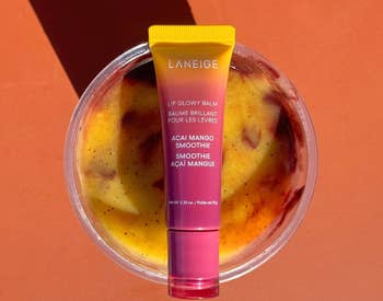 Lip balm tube on fruity smoothie background, text: