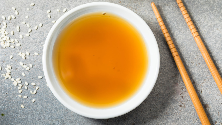 Sesame oil in a small bowl with chopsticks on the side