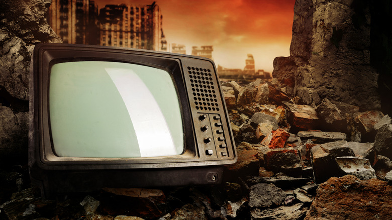 An old tube television sitting on top of building ruble
