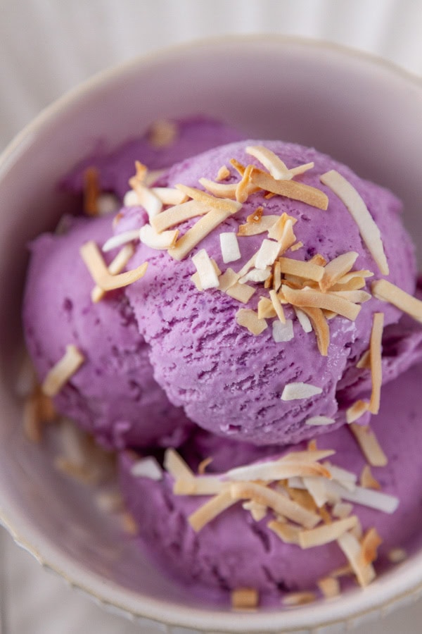 looking down into a bowl of ube ice cream with coconut garnish.
