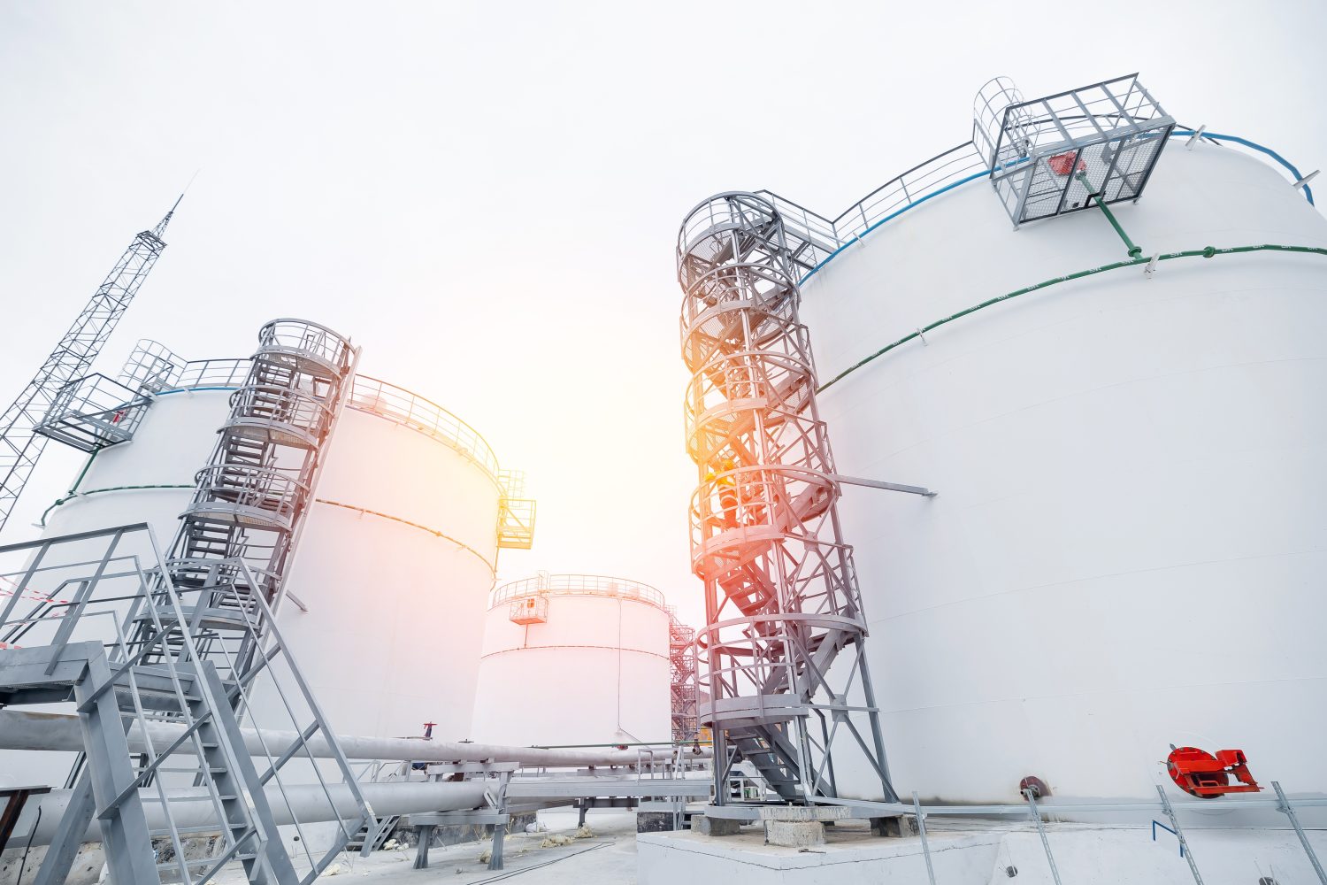Modern white oil fuel storage tank against blue sky with sunlight.