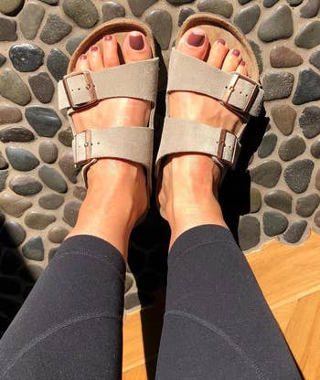 reviewer's feet wearing the beige sandals