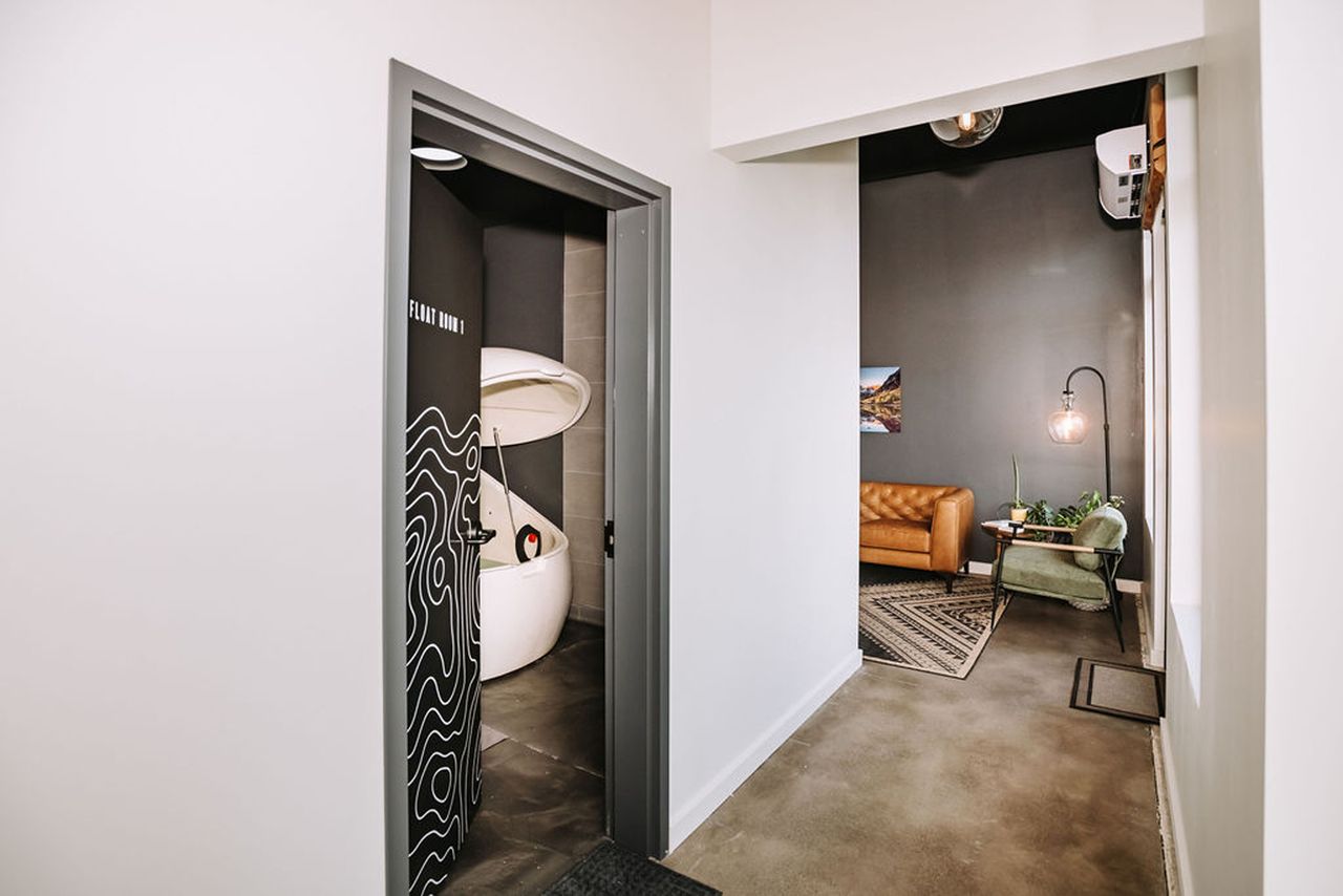 Entrance to a sensory deprivation tank room with a view of a lounge seating area in the background