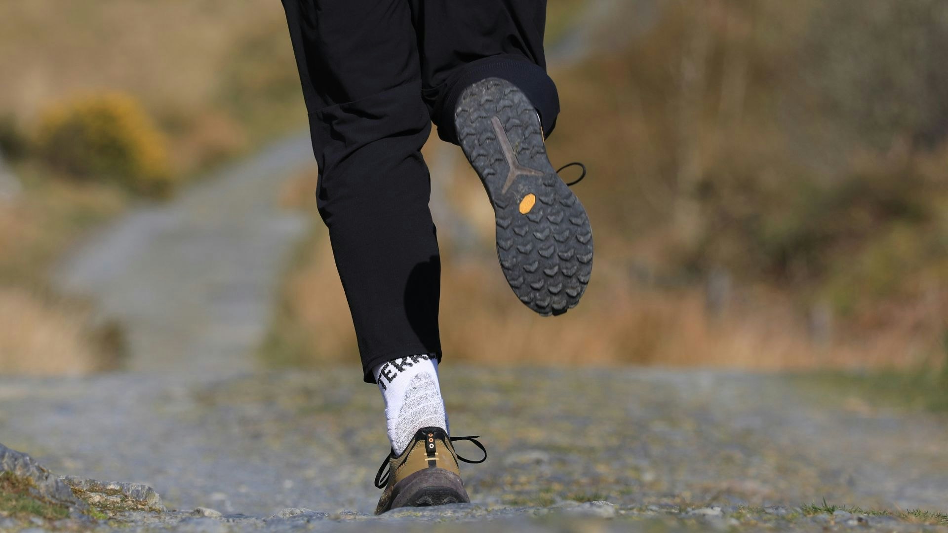 runner wearing saucony xodus ultra 4 trail running shoes on winding gravel trail