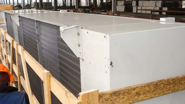 A large industrial air conditioning unit positioned on wooden pallets in a warehouse setting.