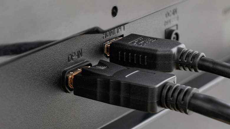 A close-up of a DisplayPort cable and HDMI cable both plugged in a device