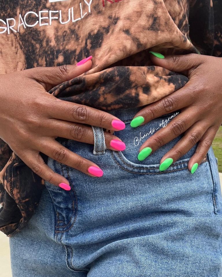Person wearing a tiedye shirt and jeans displaying brightly painted nails