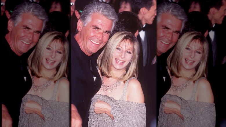 Barbra Streisand wearing a sparkly top and an ornate necklace posing with James Brolin at the 1997 Oscars.