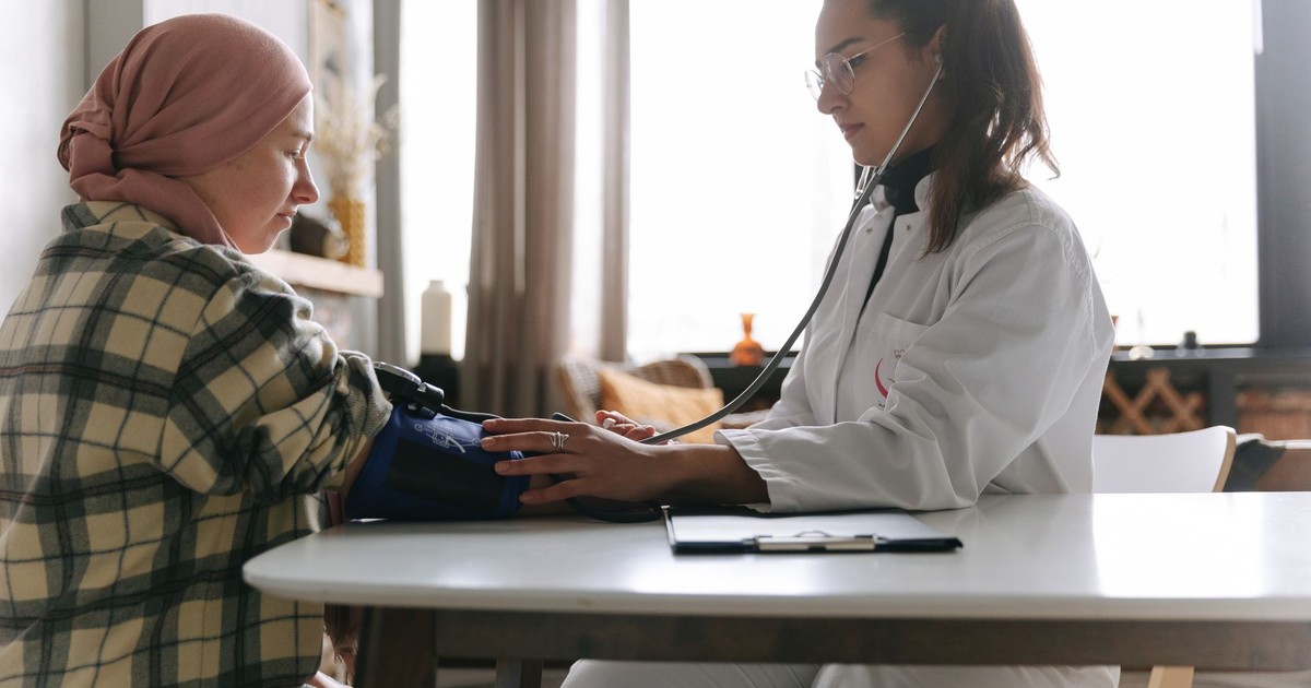 A healthcare professional measures a patient's blood pressure in a cozy indoor setting.