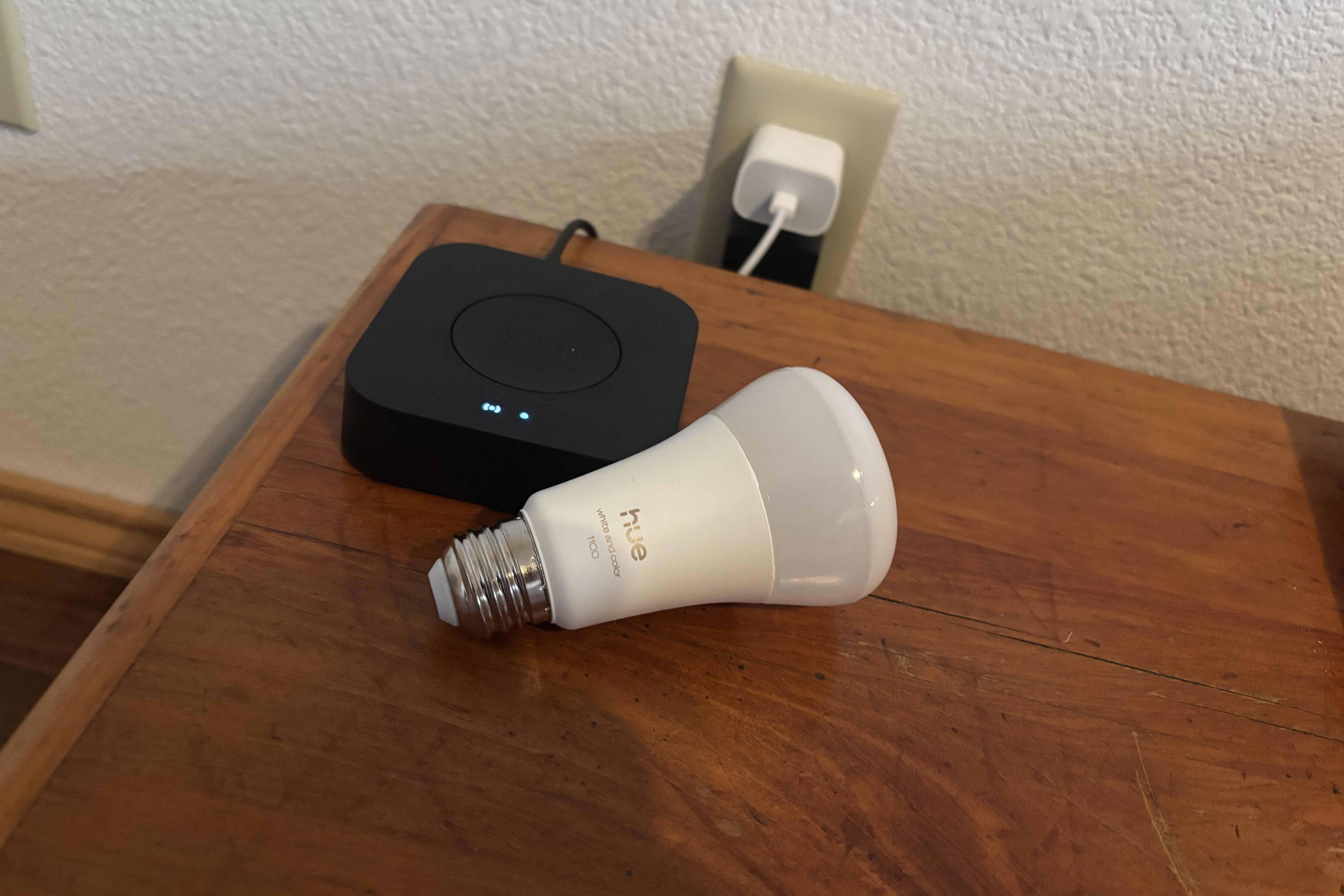 A Philips Bridge and smart bulb sit atop a wooden desk.