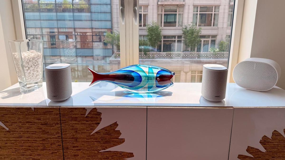 A pair of white Bose Lifestyle Speakers sitting on a table in front of a window.
