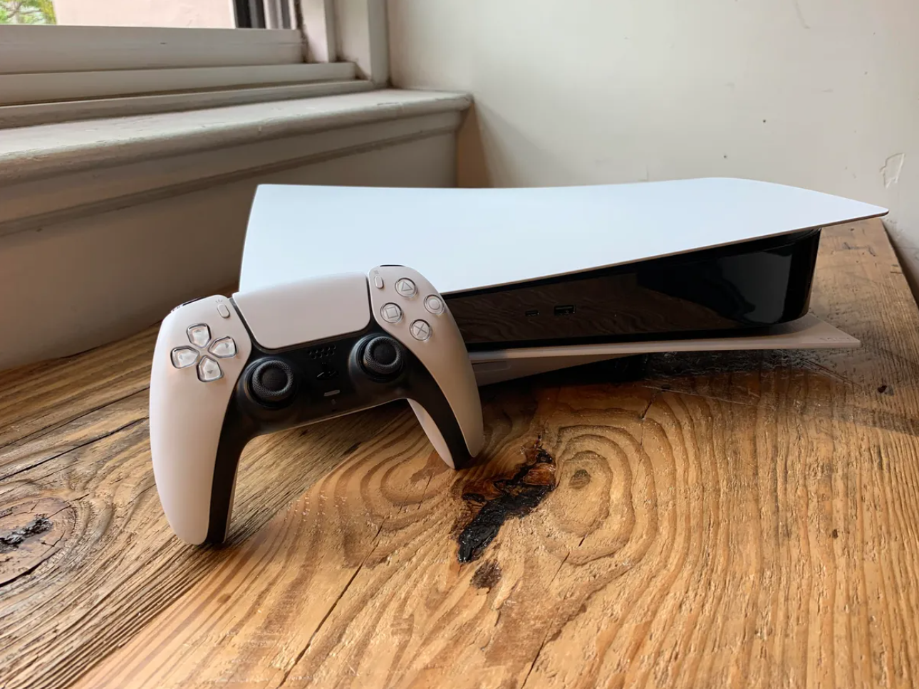 A white PlayStation 5 console and controller, set against a red background.
