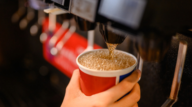 A customer getting a drink from a self-service soda fountain.