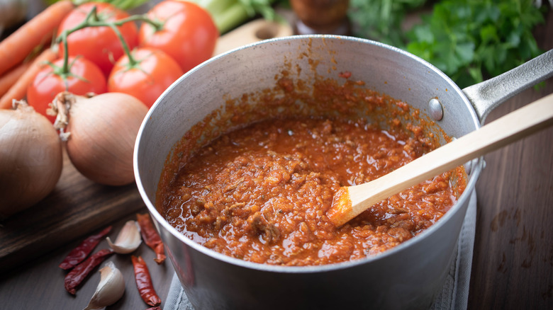 Bolognaise sauce in pot with ingredients background