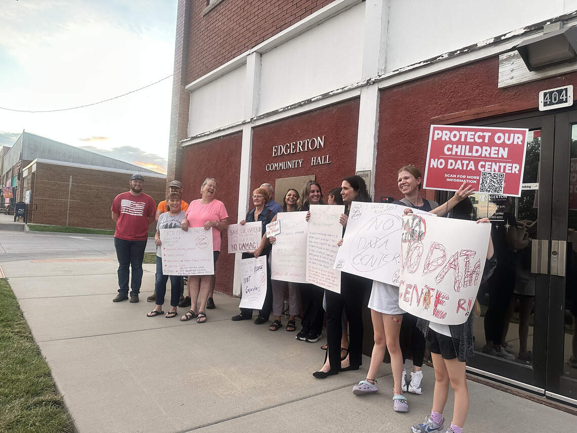 Edgerton residents pose for a photo outside the Edgerton Community Hall following the city council meeting on July 16. Residents held up signs protesting data centers.