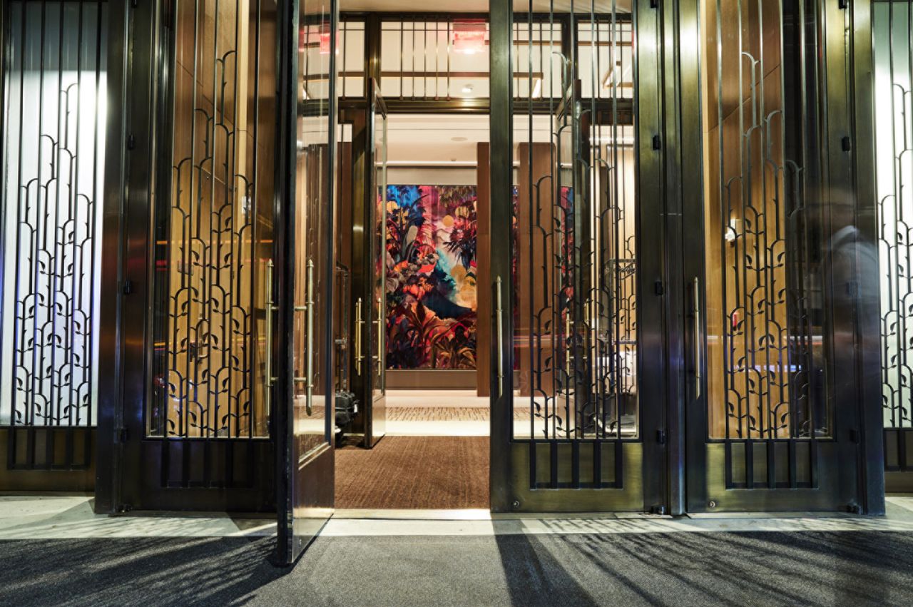 Entrance doors to a lobby with a vibrant artwork visible inside
