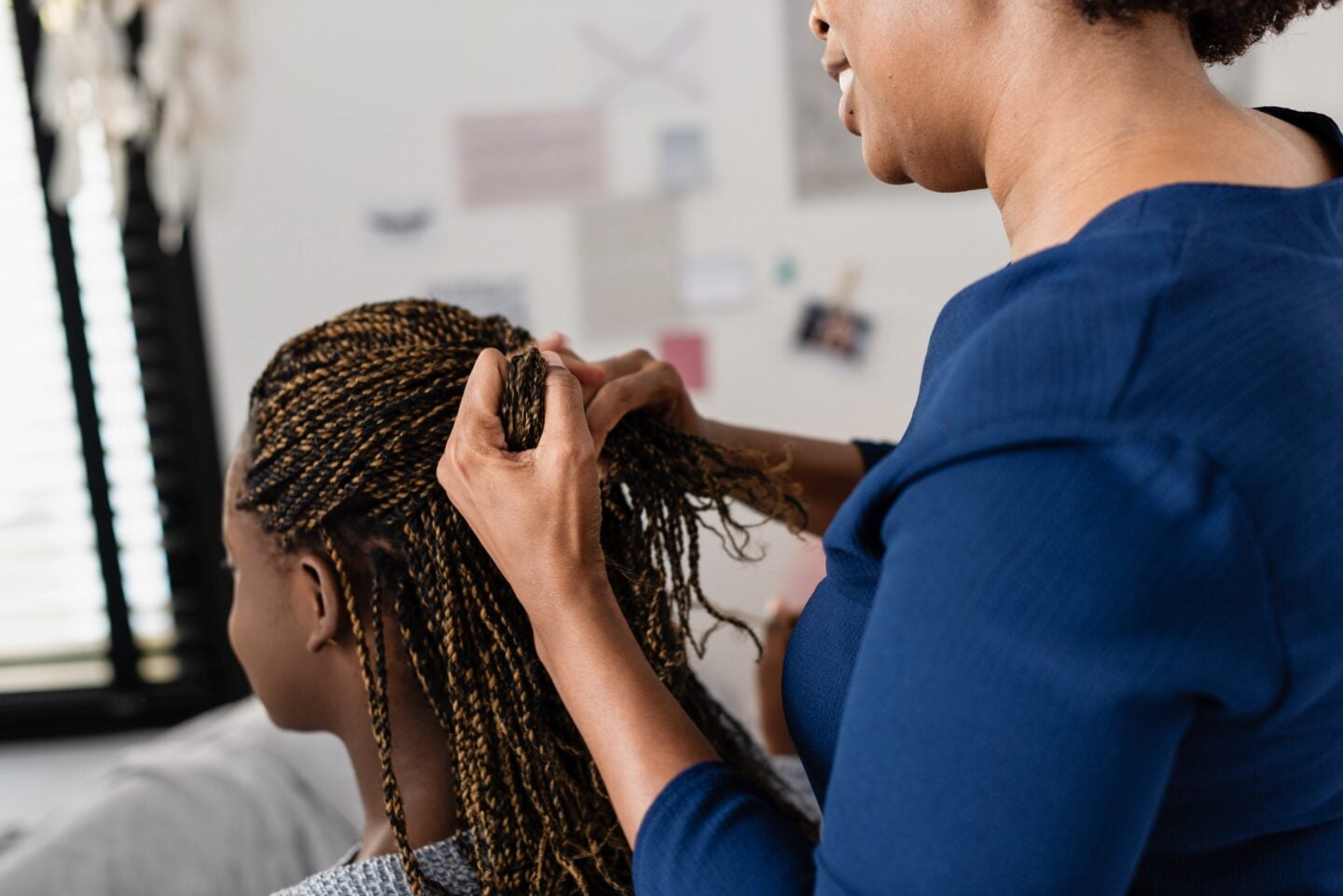 Woman braiding young girl’s hair.