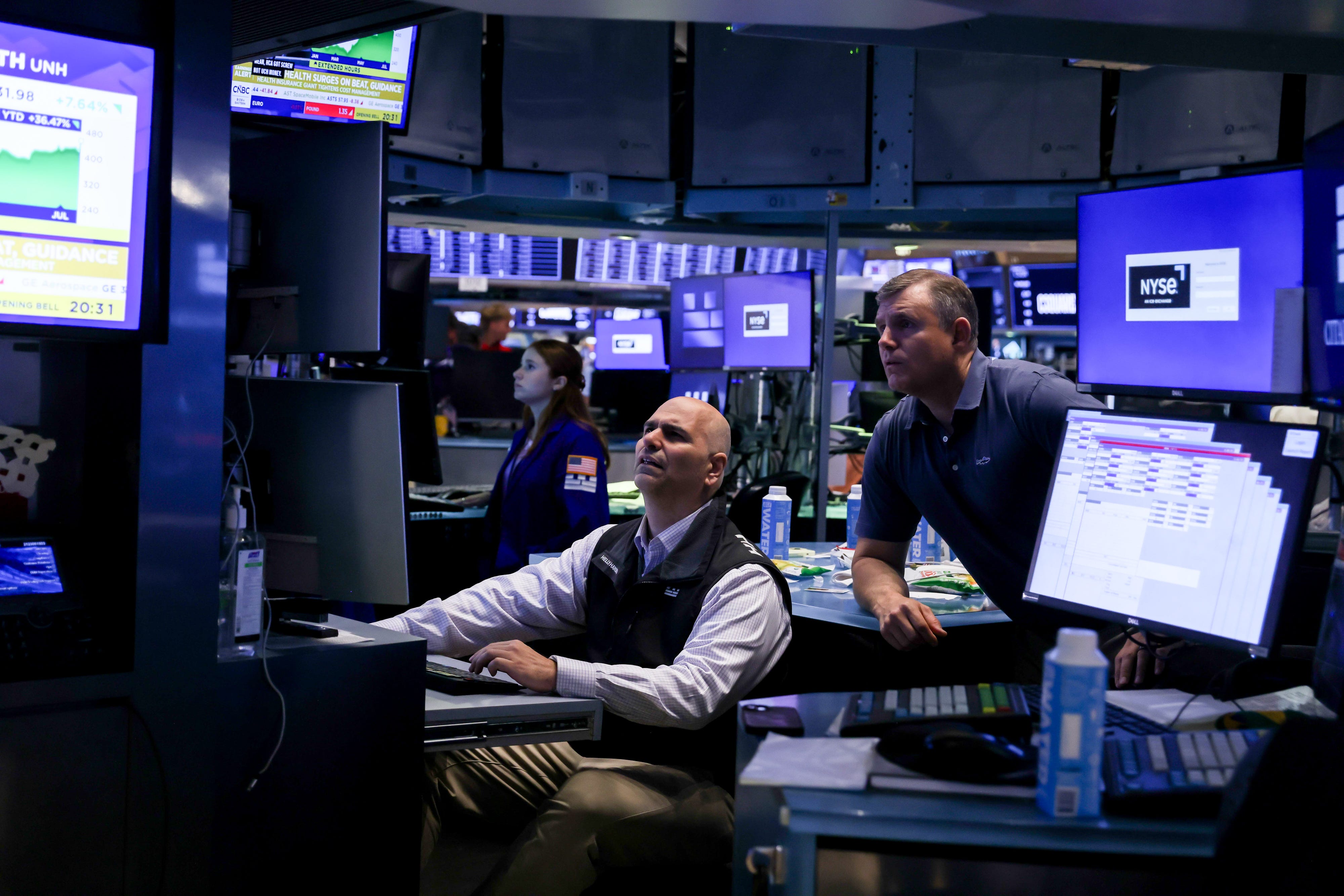 Traders working at the New York Stock Exchange looking up at a monitor
