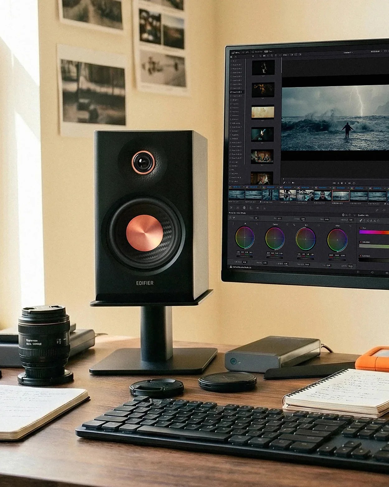 Black Edifier speaker with copper-colored cones on a black stand next to a computer monitor and keyboard on a wooden desk.