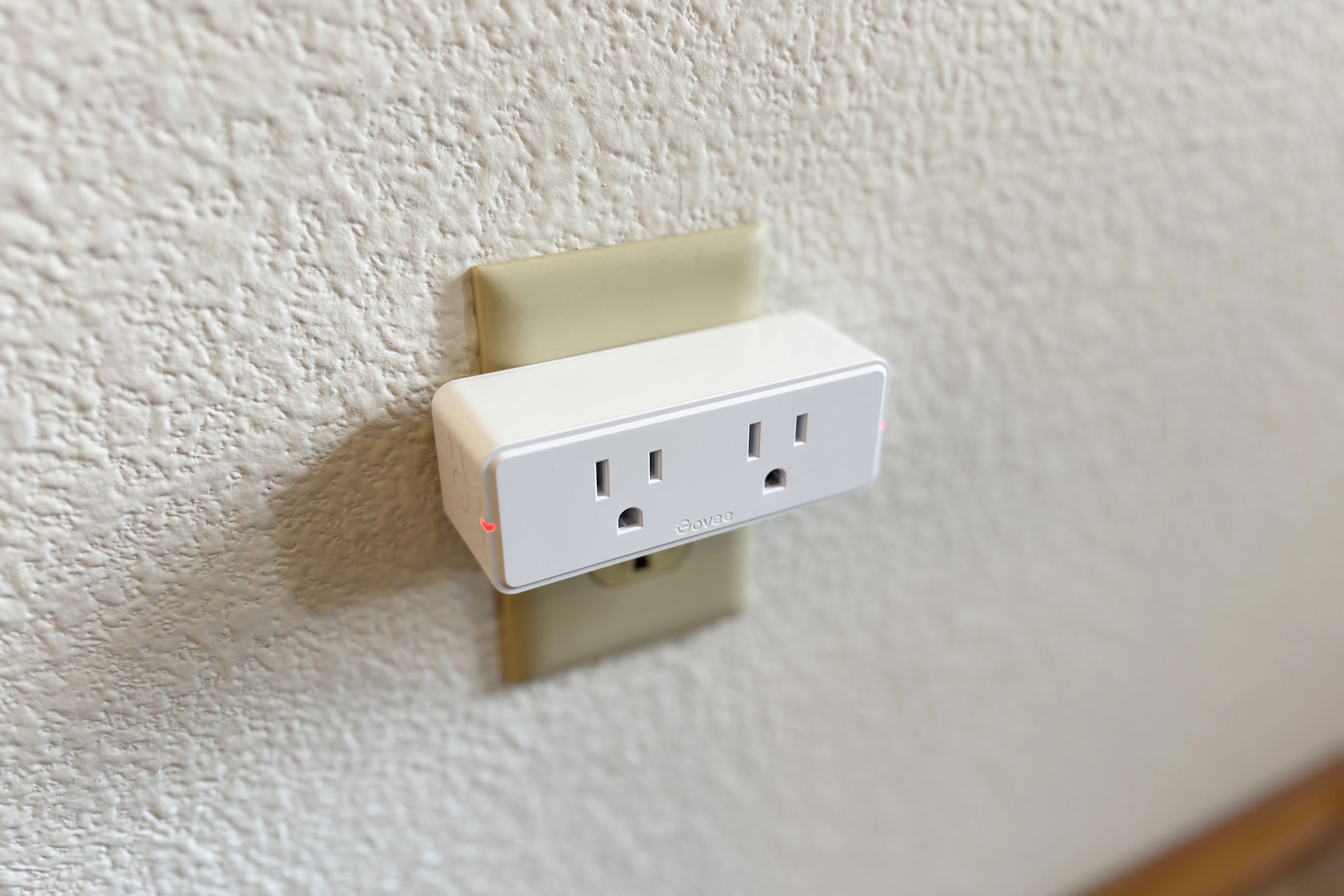 Govee's white dual smart plug on an outlet on a white wall.