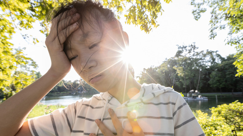 Woman with hand on forehead and chest in heat