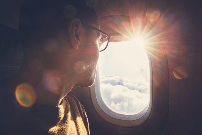 Person in airplane seat, looking out window.