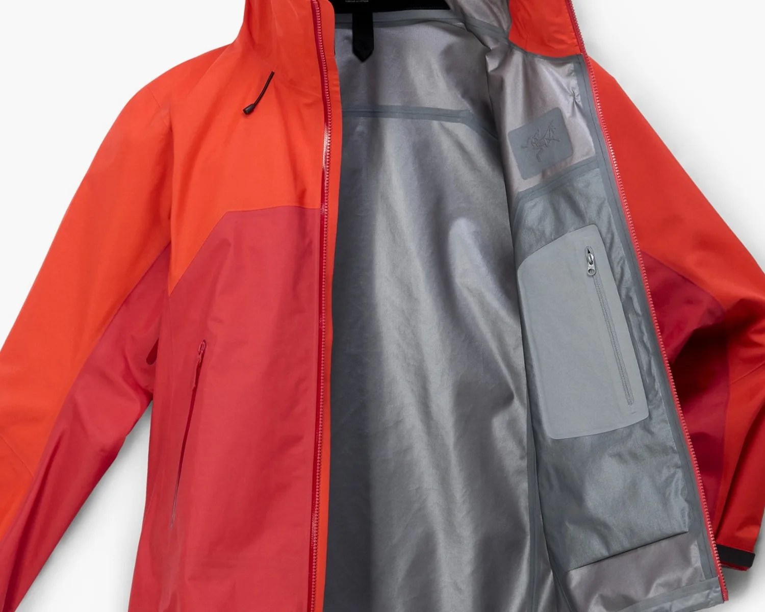 Red and orange waterproof jacket with gray inner lining and zippered inner pocket.