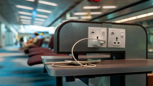 USB charging station in an airport with a phone plugged in.