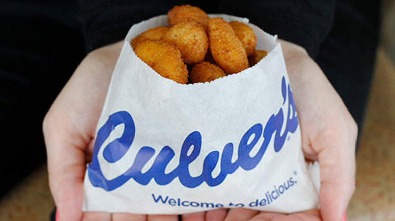 Person cupping their hands to hold a paper bag full of Culver's cheese curds