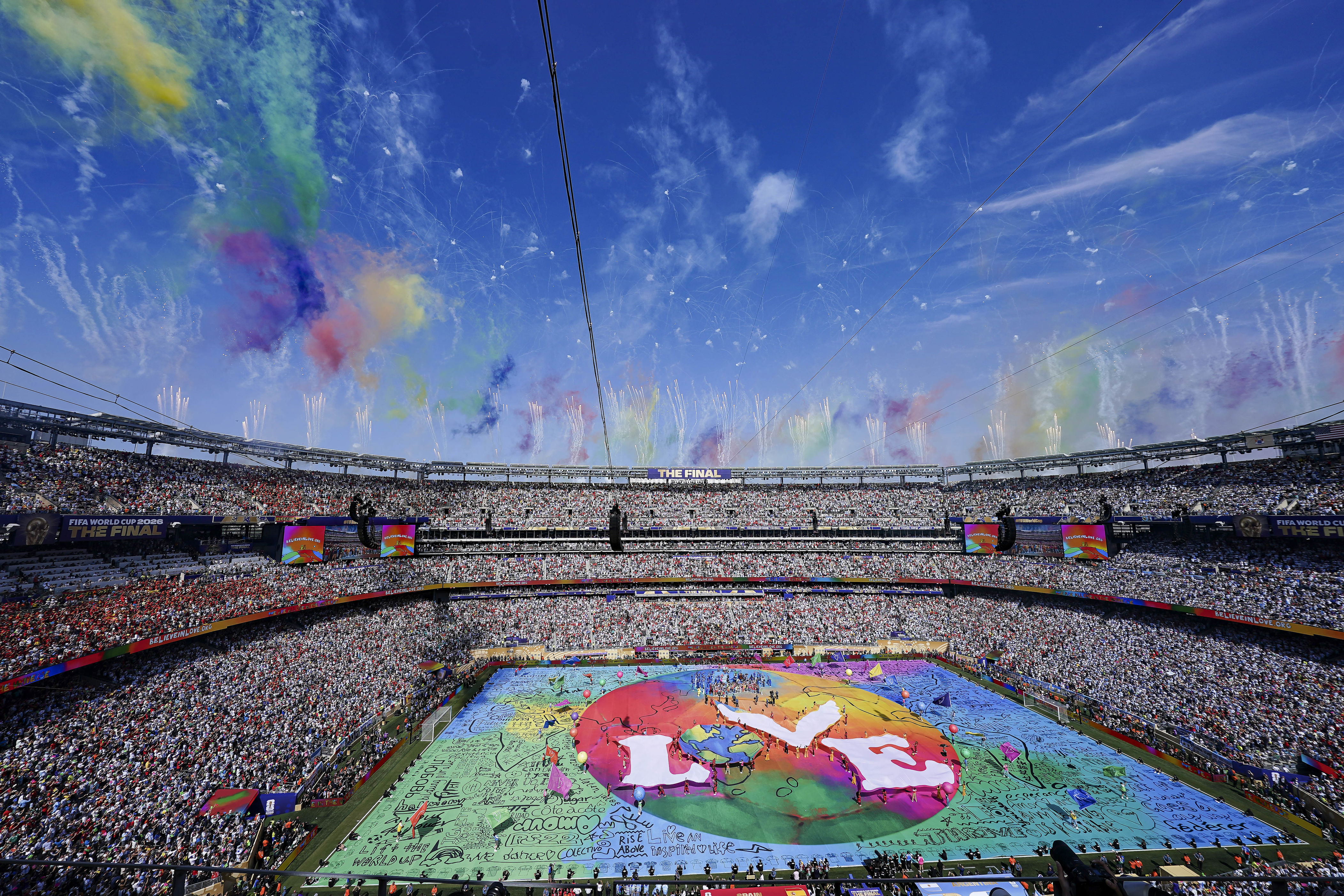 MetLife Stadium during the World Cup Halftime Show, with a colorful field covered in a vibrant Earth design that reads