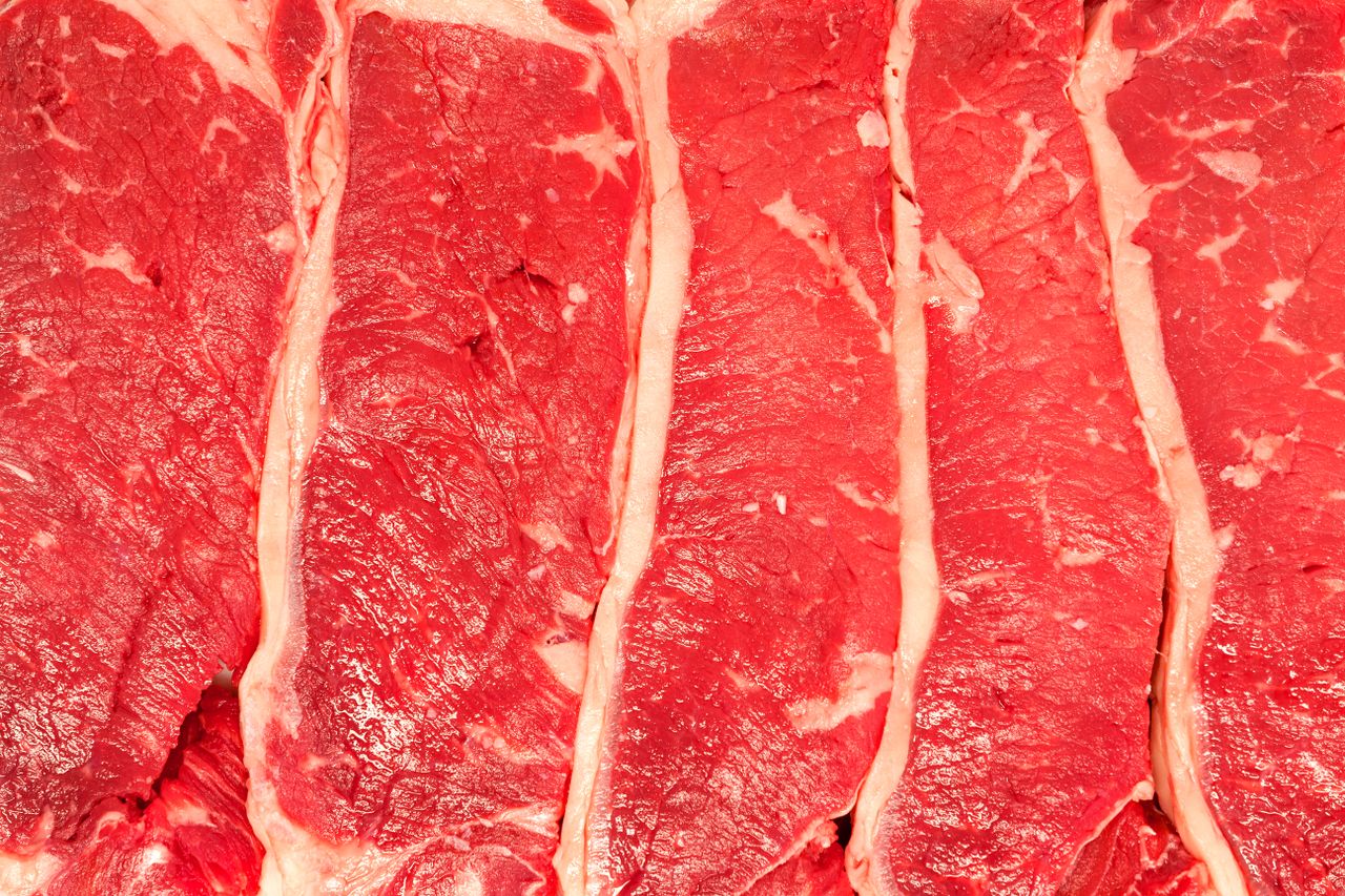 Several raw steak cuts closely arranged showing detailed marbling and texture