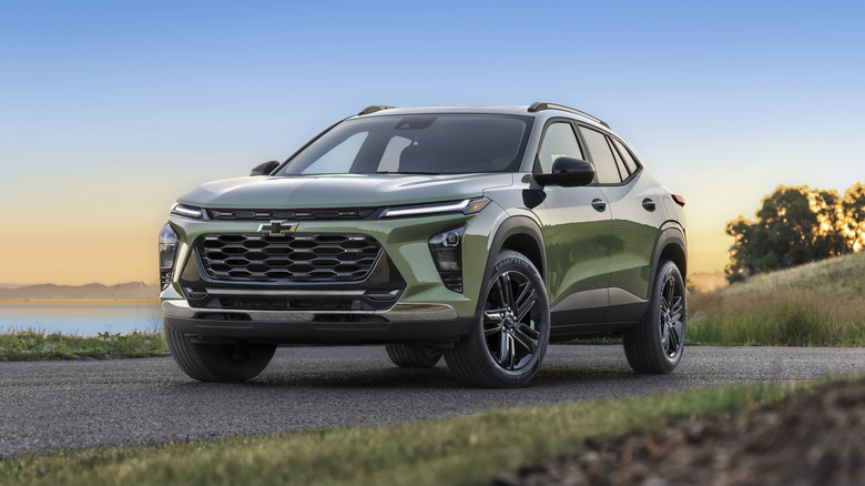 A green 2026 Chevrolet Trax on pavement at sunset with a lake in the background