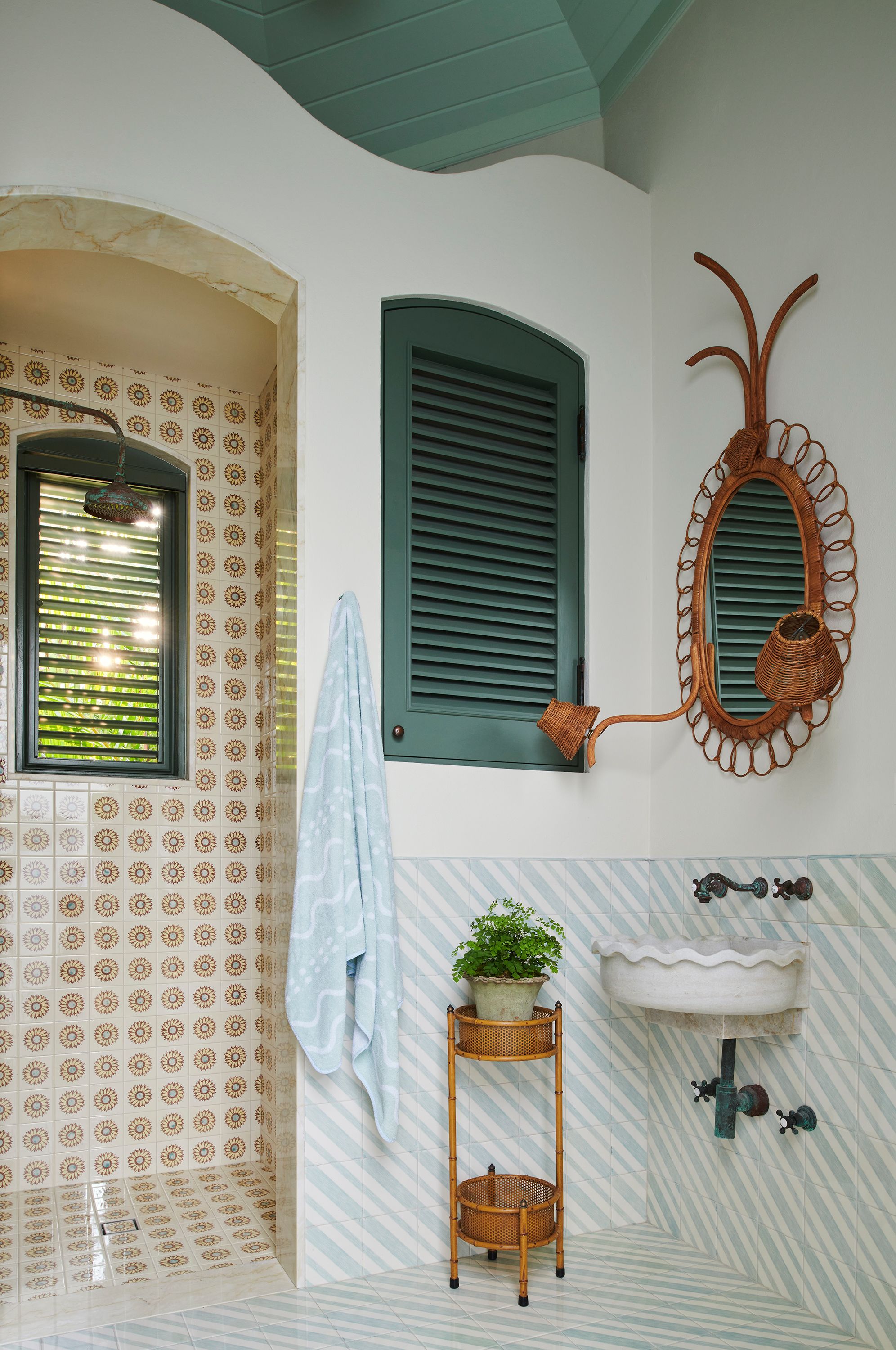 The octagonal poolhouse by Wyeth was an architectural treat for Graziolo, who incorporated a served interior wall to play up the structure’s original inspiration: a Charleston folly. A rattan mirror with curving sconces and squiggle-decorated towels play off the intervention.
