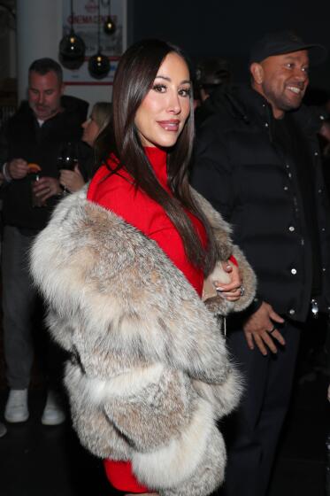 Angie Katsanevas wears a red ensemble with fur coat at a party.