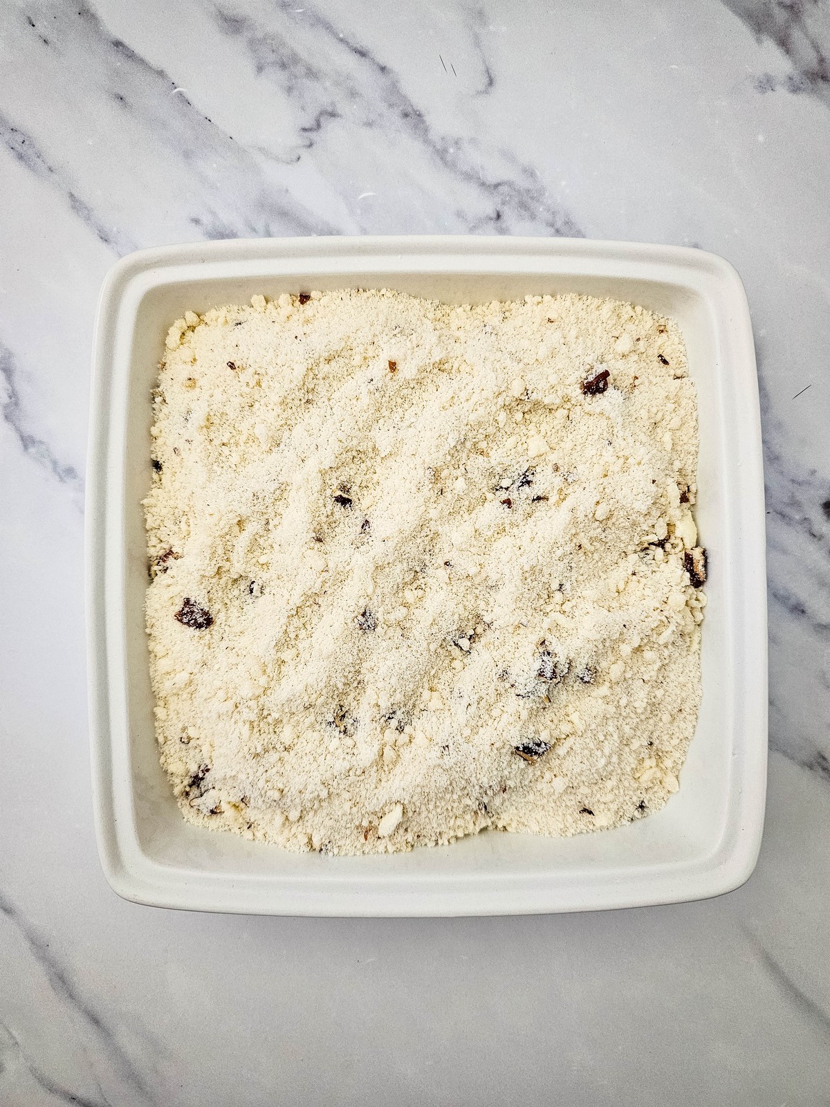 Crumble topping spread over apple pie filling in the baking dish