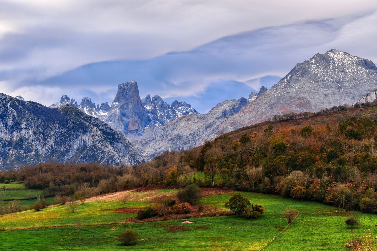 Mountain range landscape with grassy fields in the foreground notable peaks in the distance