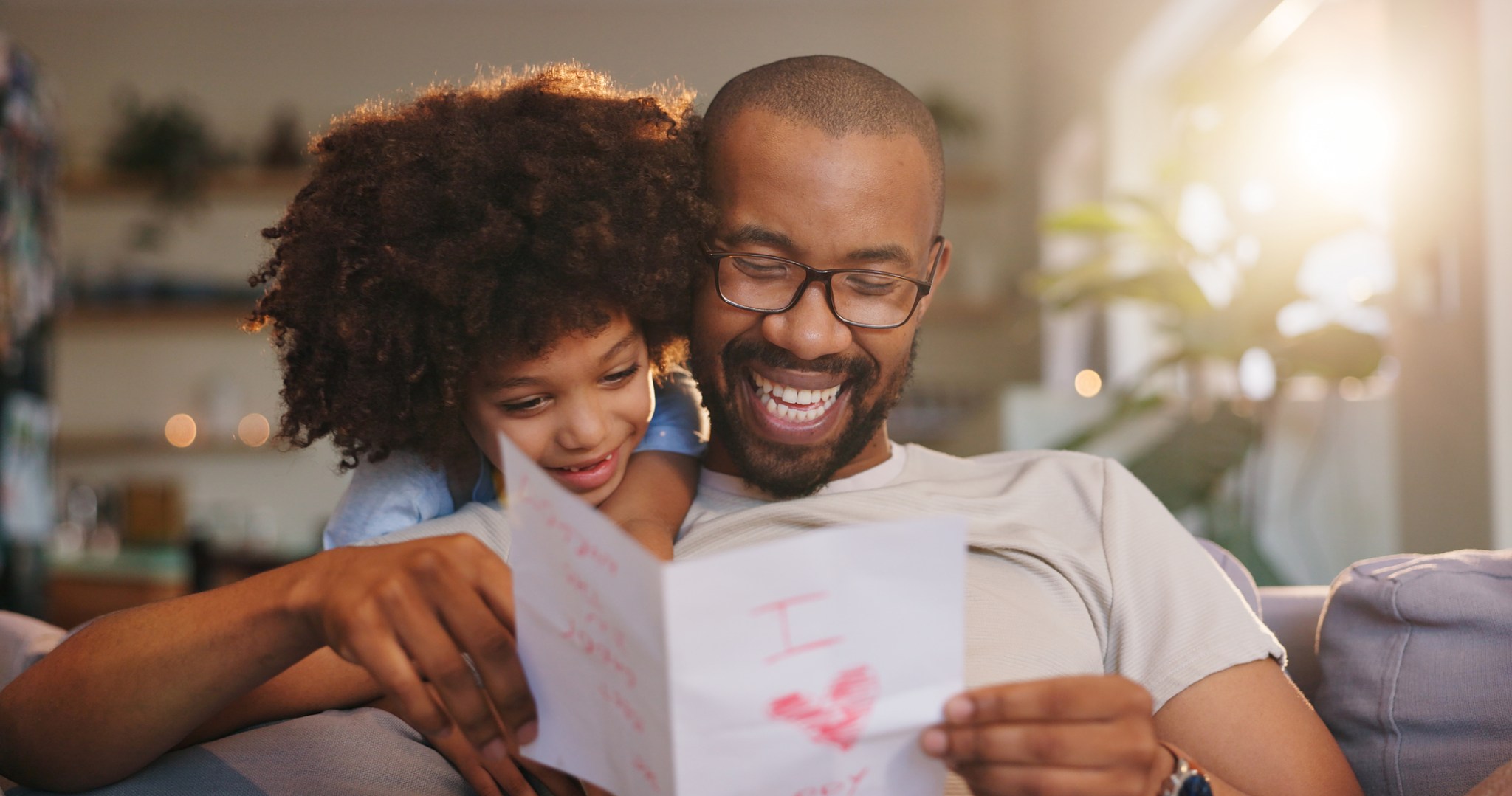 Happy dad, letter and relax with son for love, gift or present on sofa for fathers day surprise at home. Papa, child or little boy with smile for special note, appreciation or gratitude for childhood