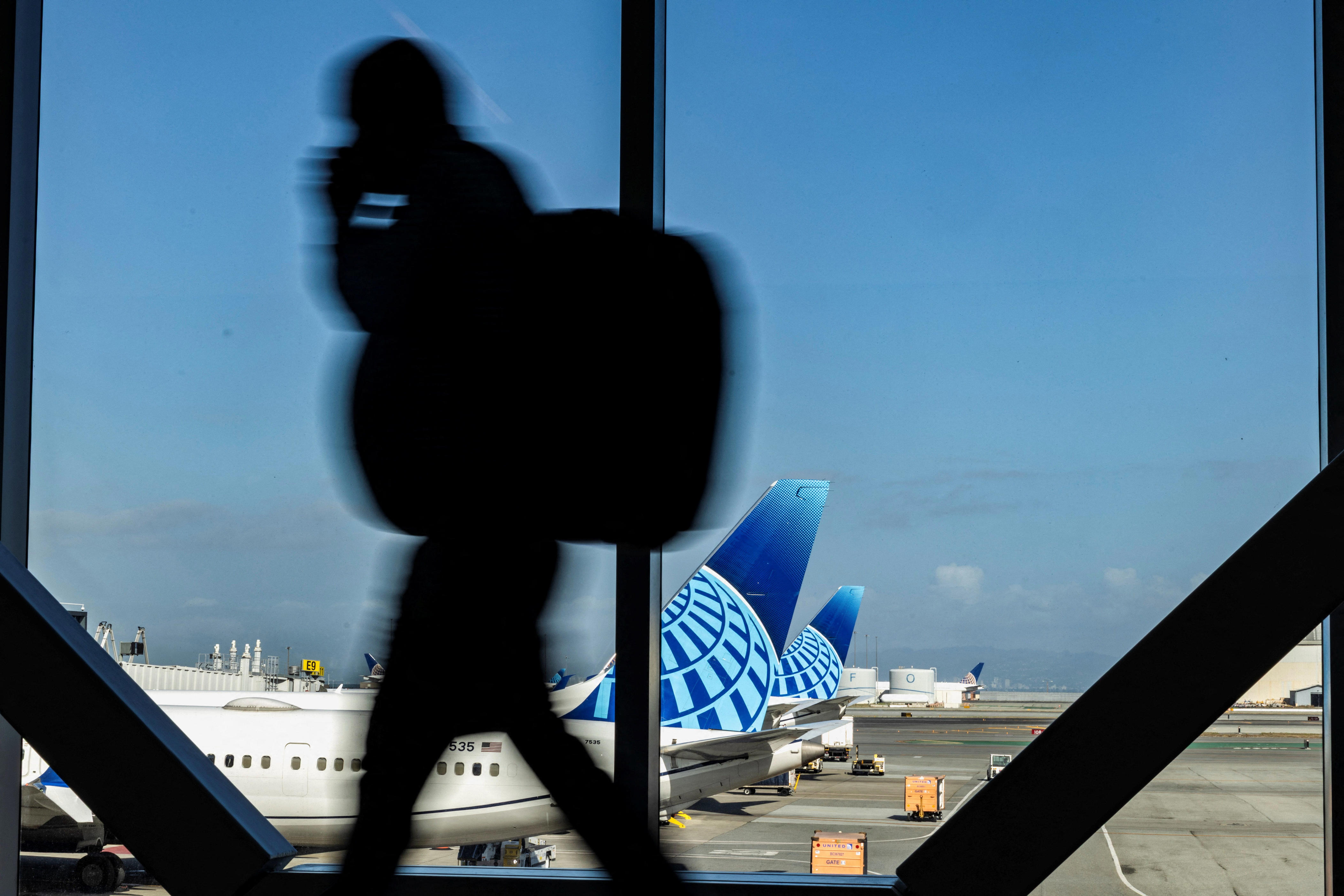 A passenger walks by as commercial airplanes sit at San Francisco International Airport in San Francisco on Nov. 6, 2025.