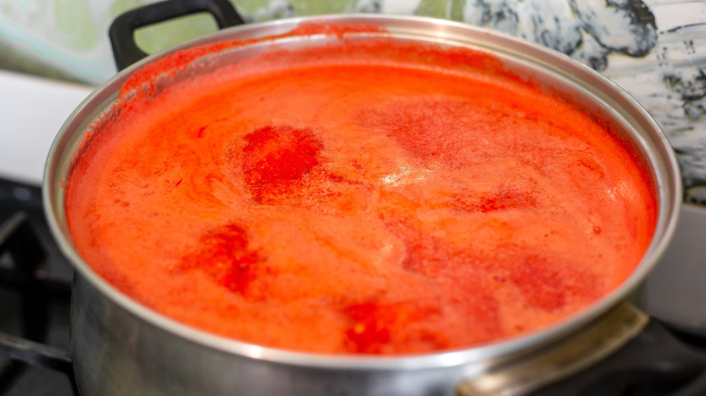 Tomato sauce simmering in large stainless steel pot on a stove